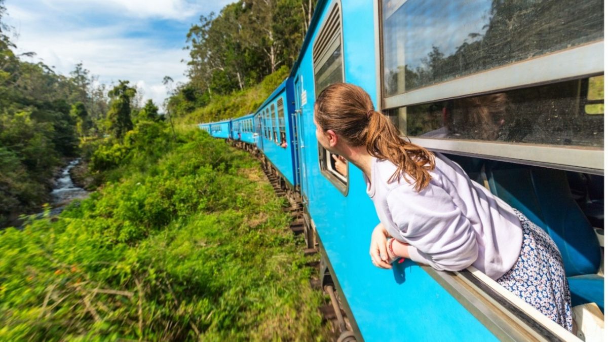 A woman looks out a train window during one of the most scenic day trips from NYC by train through the Hudson Valley