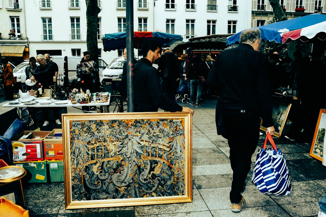 A smiling artist arranges colorful paintings at a New York City street fair booth