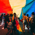 Thousands of people lining Fifth Avenue to watch the NYC Pride march, waving rainbow flags in Manhattan