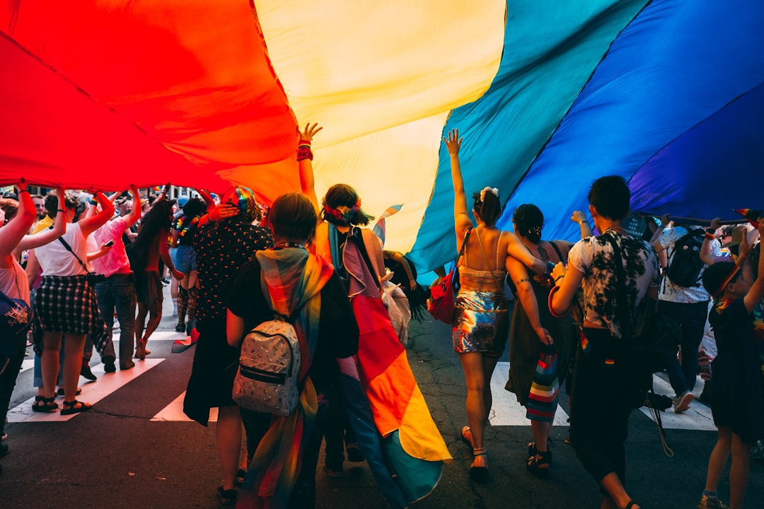Thousands of people lining Fifth Avenue to watch the NYC Pride march, waving rainbow flags in Manhattan
