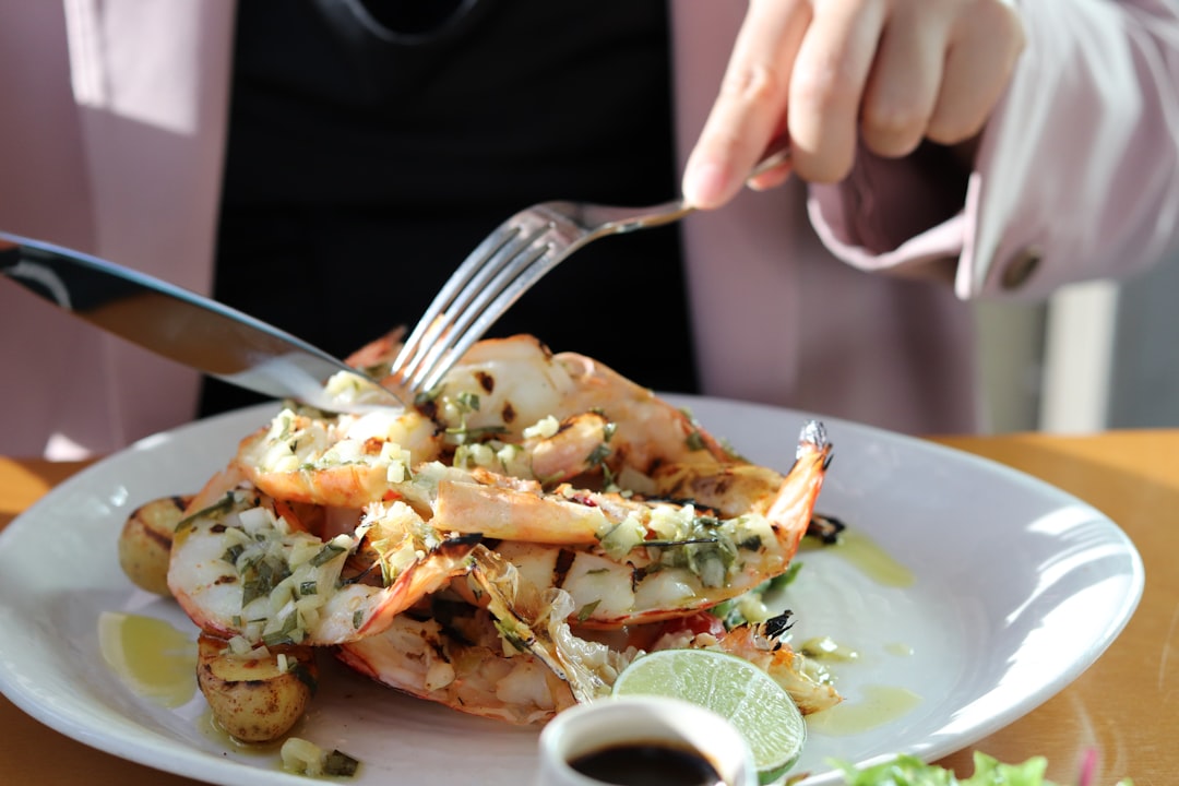 A woman enjoys fresh lobster rolls at a waterfront restaurant in New York City on a sunny June afternoon.