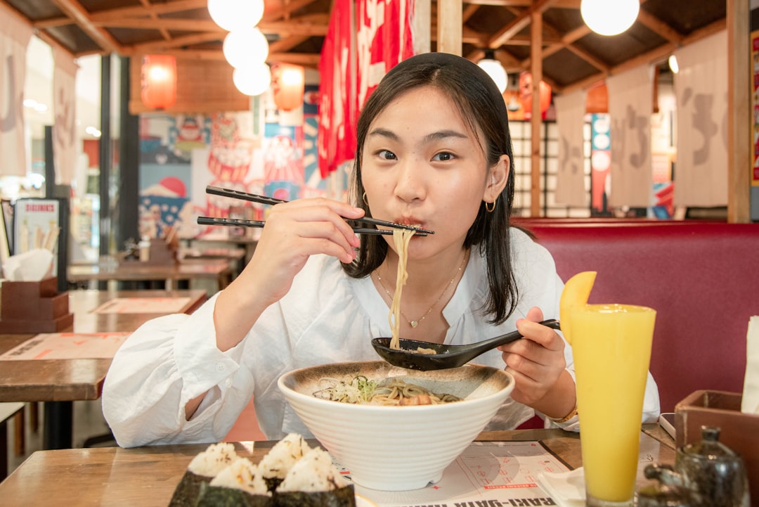 A woman carefully lifts a soup dumpling with chopsticks at a table in Flushing Chinatown, New York