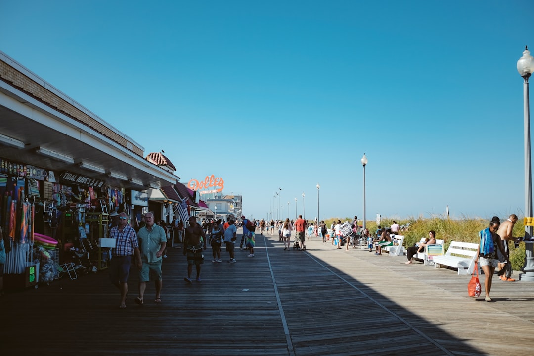 A woman walks along a sunny Jersey Shore boardwalk on a summer weekend trip from New York City