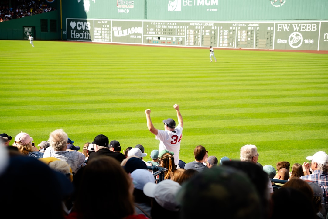 A smiling fan cheering in the upper deck while watching a baseball tickets game on a sunny summer afternoon