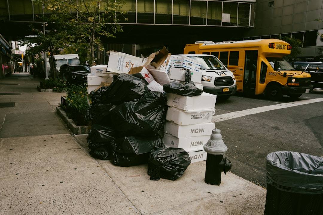overflowing garbage bags and cardboard boxes piled on New York City sidewalk at night beside a fire hydrant.