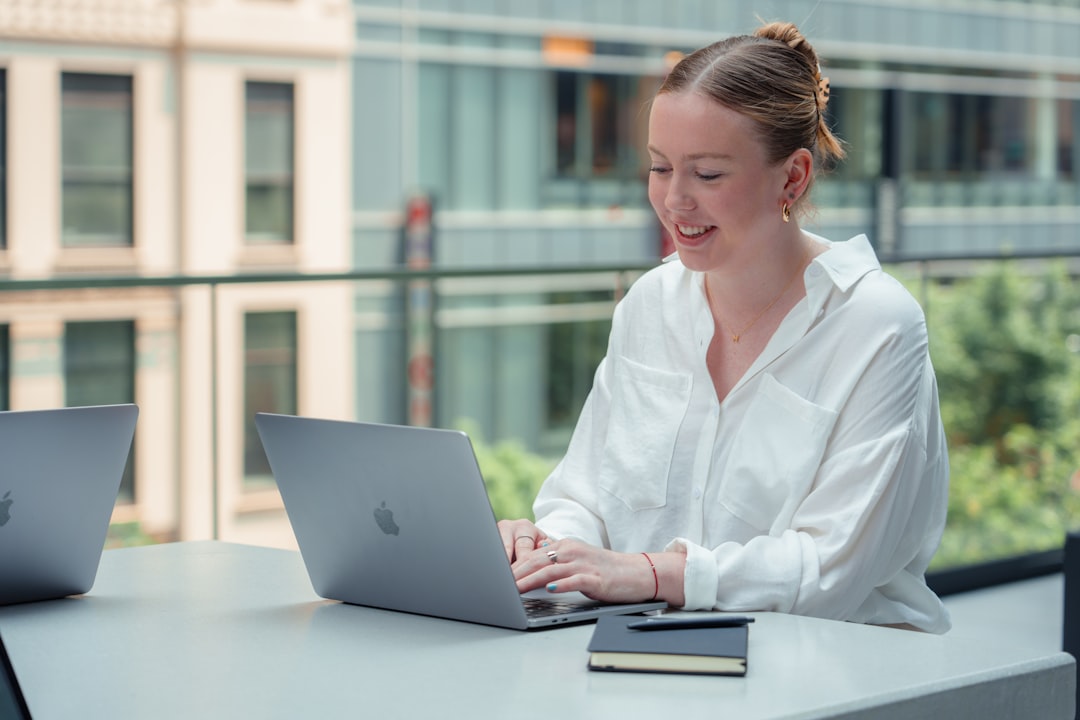 A professional woman works at a laptop inside one of New York City's best co-working spaces, with modern open-plan desks.