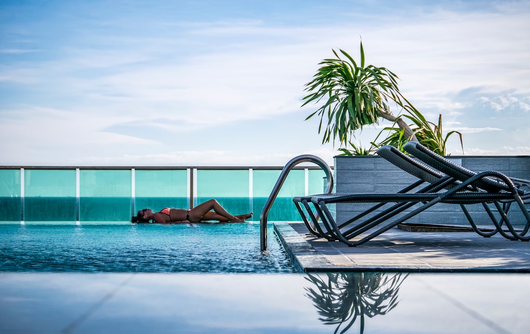 A woman resting by one of Manhattan's rooftop pools on a sun-drenched terrace with city skyline views behind her