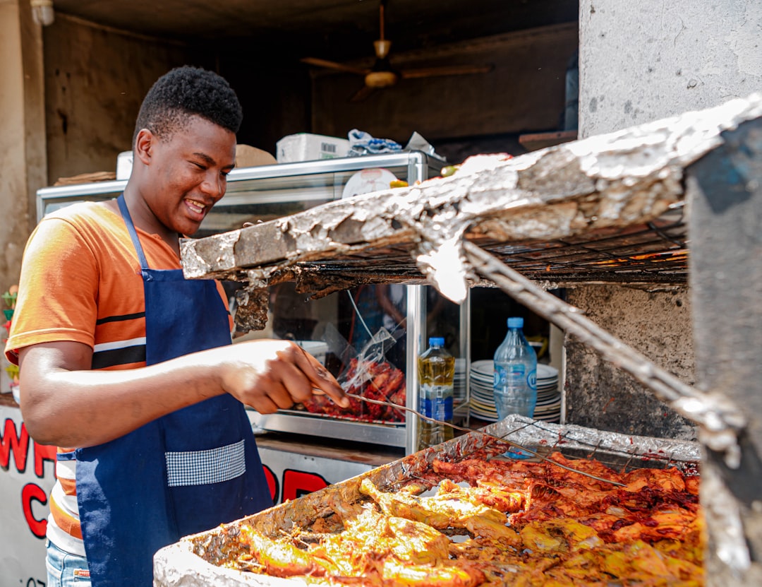 A West African man serves a bowl of fufu and soup at a busy Bronx restaurant, representing the heart of the West African food