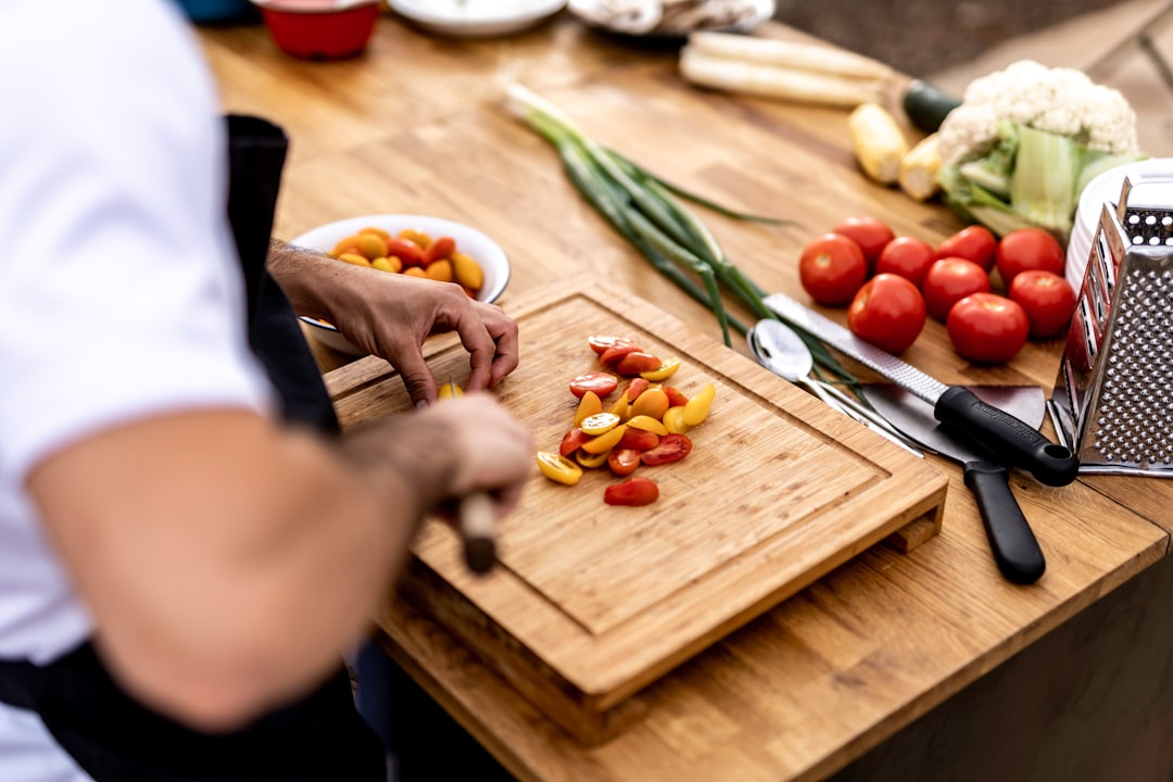 A chef carefully plates a vibrant heirloom dish featuring August tomatoes at a New York City farm-to-table restaurant.