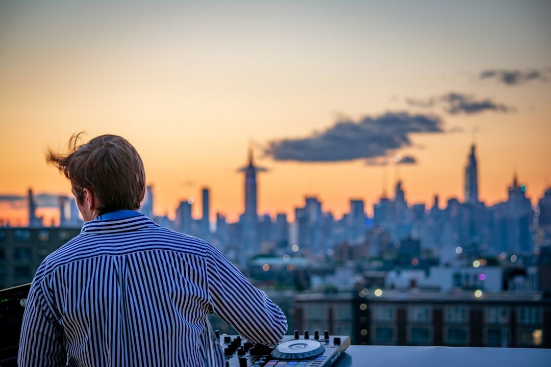 A man enjoying a cocktail on a Manhattan rooftop terrace at the city's top private clubs with a skyline view behind him