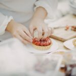 A pastry chef carefully plates a late summer dessert at a New York City restaurant, showcasing seasonal fruit.