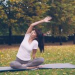 A woman practicing yoga on a mat at an outdoor fitness class in a New York City park