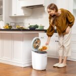 A woman placing food scraps into a countertop bin as part of her daily composting routine in a New York City kitchen.