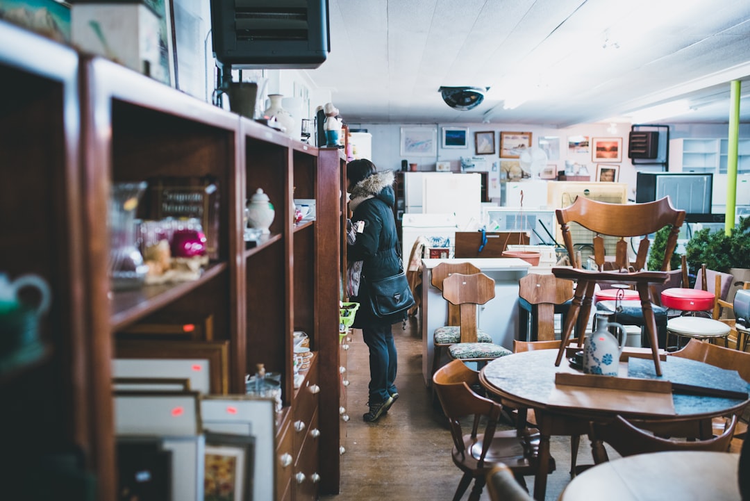 A woman carefully inspects a vintage furniture piece in a Manhattan dealer showroom, evaluating provenance and condition