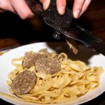 A chef shaves fresh Alba white truffle over handmade pasta at one of New York City's most celebrated truffle dinners