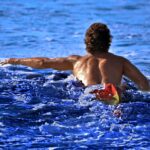 A swimmer wading into the open water at Brighton Beach, representing the open-water culture of a New York City swimming club