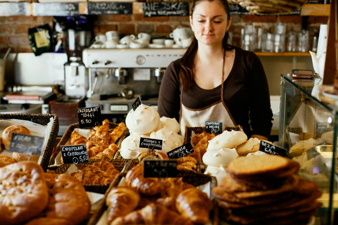 A woman carefully selecting a pastry at a gluten-free bakeries counter in New York City, surrounded by baked goods.