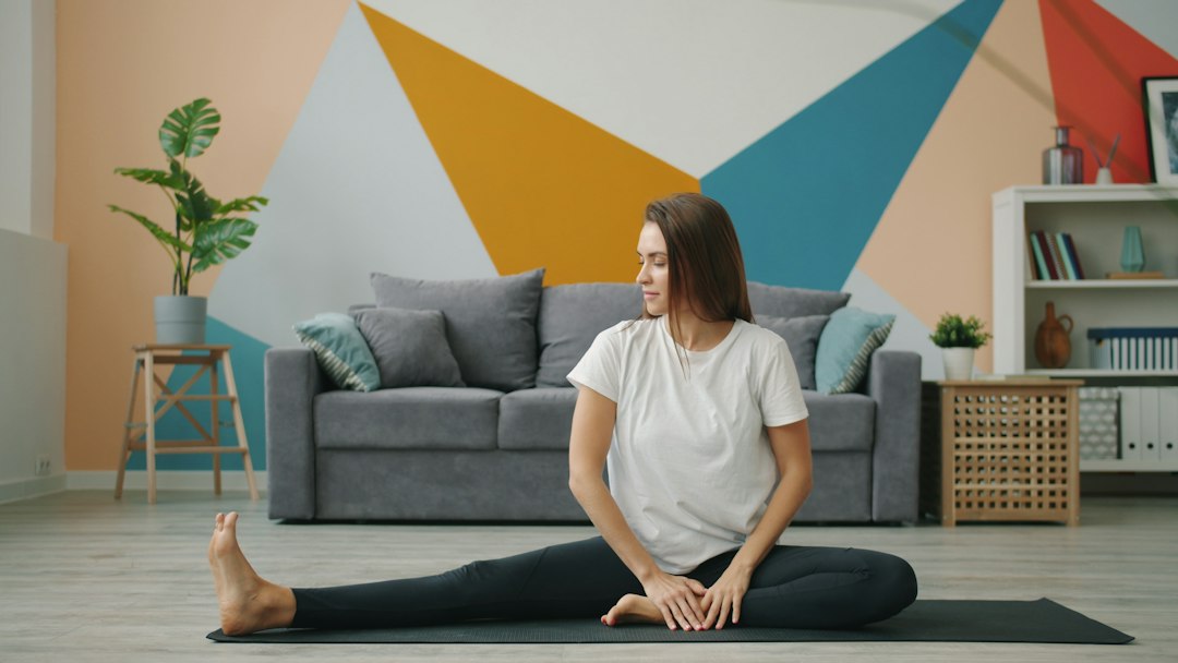 A woman practicing a recovery routine on a yoga mat in a compact New York City apartment, surrounded by soft morning light